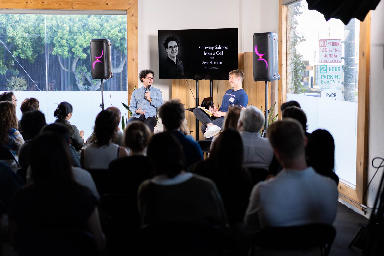 Aryé Elfenbein of Wildtype and Cam Wiese on stage in front of a full room at a Pioneers talk